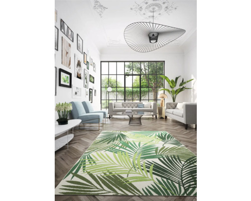 Wohnzimmer mit Sofa, Sessel, Zimmerpflanzen und Teppich mit Blattmuster