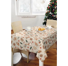 Festlich gedeckter Tisch mit Lebkuchenmuster Tischdecke und Weihnachtsbaum im Hintergrund
