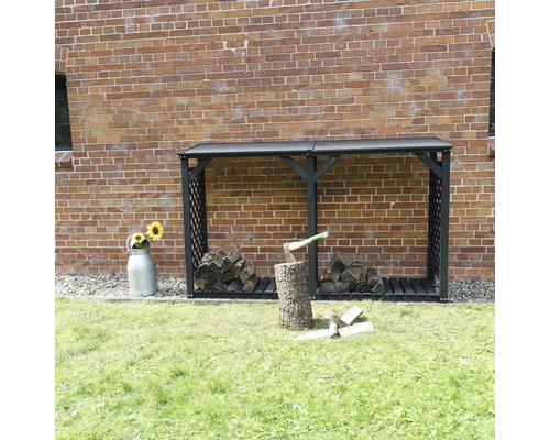 Kaminholzunterstand promadino Speyer inkl. Erweiterung 238 x 68 x 148 cm anthrazit Holzlagerregal vor einer Backsteinmauer mit gelagertem Holz und einem Hackklotz mit Axt