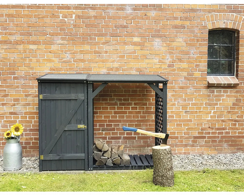 Kaminholzunterstand, Geräteschrank promadino Speyer 192 x 68 x 148 cm anthrazit Holzlager mit Tür, gehacktem Holz und Axt vor einer Backsteinmauer