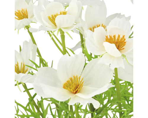 Nahaufnahme von künstlichen weißen Blumen mit gelben Akzenten und grünen Stielen.