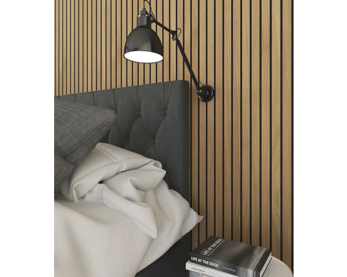 Schlafzimmerszene mit Bett, Wandlampe und Bücherstapel