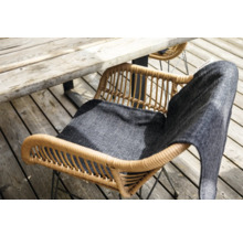 Gartenszene mit Rattan-Gartenstuhl und Sitzkissen unter Holztisch