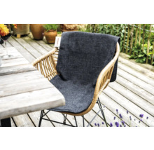 Rattan Gartenstuhl mit grauer Sitzauflage auf einer Holzterrasse