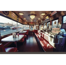 Innenansicht eines Diner-Restaurants im Retro-Stil mit Sitzbänken, Tischen und Jukebox