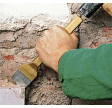 Handwerker arbeitet mit einem Hammer und einem Meißel an einer Mauer.