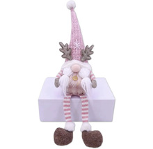 Dekorativer Weihnachtswichtel mit Mütze, Geweih und gestreiften Beinen sitzt auf einer weißen Oberfläche