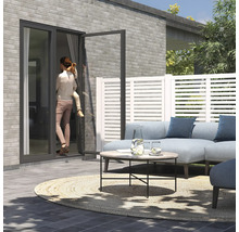 Terrasse mit Loungemöbeln, Zaunelementen und einer Frau mit Kind an einer Terrassentür