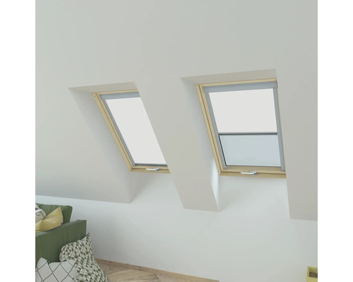 Zwei Dachfenster mit geöffnetem Fenster und Rollo in einem Dachzimmer