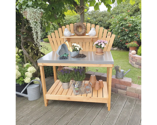 Gartenszene mit einem Pflanztisch aus Holz mit Metallplatte und Gartenzubehör