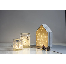 Dekorative Szene mit Glaswindlichtern und einem Adventskalenderhaus, beleuchtet mit Lichtern