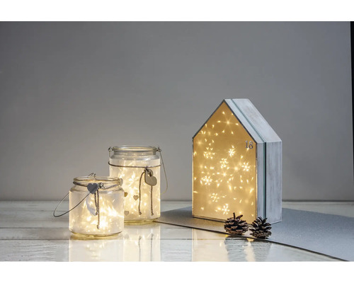 Dekorative Szene mit Glaswindlichtern und einem Adventskalenderhaus, beleuchtet mit Lichtern