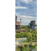 Industrieanlage mit alten Stahlkonstruktionen und grüner Vegetation im Vordergrund