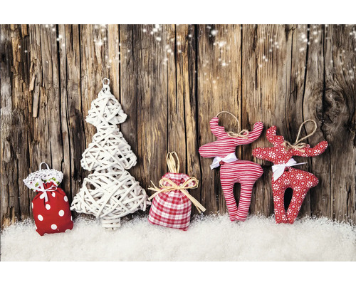 Weihnachtliche Dekoration mit Geschenksäckchen, Baum und Rentieren auf Schnee vor Holzwand