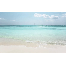 Ein heller Sandstrand mit türkisfarbenem Meer und einem Segelboot am Horizont