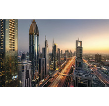 Panoramaaufnahme der Skyline von Dubai mit beleuchteten Wolkenkratzern und Straßenverkehr bei Dämmerung.