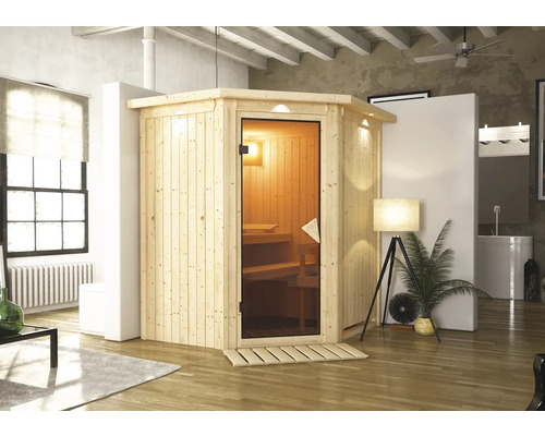 Plug & Play Sauna Karibu Achat III inkl. 3,6 kW Ofen u.integr.Steuerung mit Dachkranz und bronzierter Ganzglastüre Ecksauna aus Holz mit Glastür in einem Wohnraum.