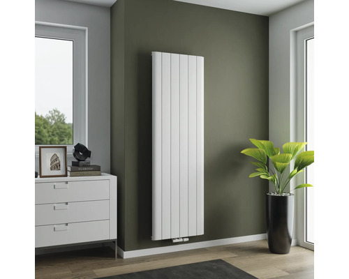 Vertikaler Heizkörper im Wohnraum mit Kommode und Zimmerpflanze.