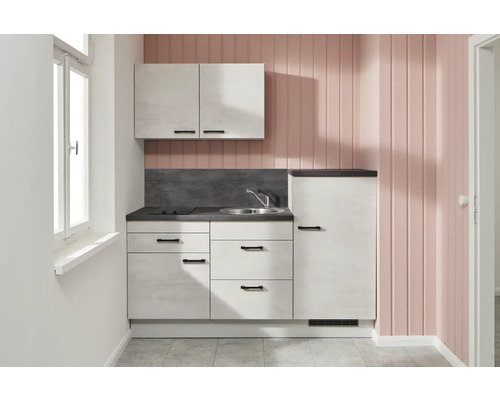 Kleine Küchenzeile mit Spüle, Kochfeld, Hängeschrank und Kühlschrank in einem hellen Raum.