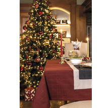 Festlich gedeckter Tisch mit Weihnachtsbaum im Hintergrund für eine stimmungsvolle Atmosphäre.