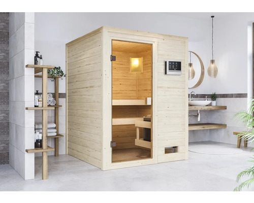 Helle Holzsauna mit Glastür und Bedienelement in einem Badezimmer mit Waschbecken und Regal.