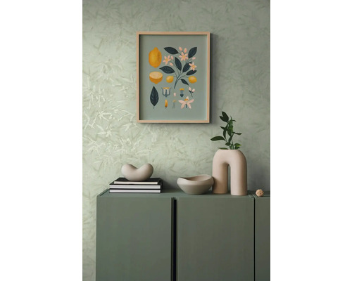 Dekorative Szene mit einer Kommode, darauf eine Dekoschale, Bücher und eine Vase, an der Wand ein Bild mit Zitronenmotiven