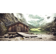 Hölzerne Hütte mit Anlegesteg an einem See vor Bergkulisse