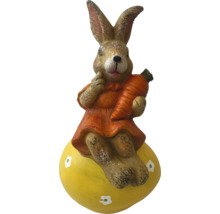 Dekorative Hasenfigur mit Karotte auf gelbem Ei für die Osterzeit