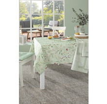 Gedeckter Esstisch mit floraler Tischdecke, Stühlen und Speisen im hellen Raum.