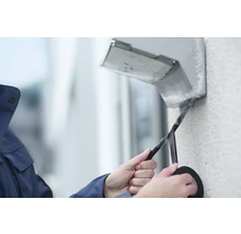 Ein Elektriker isoliert ein Kabel mit Isolierband an einer Wandleuchte.