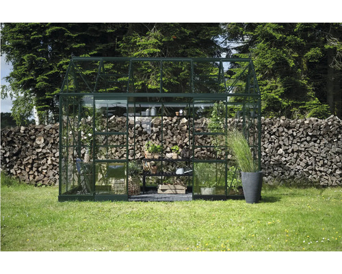 Gewächshaus mit Pflanzen und Gartenzubehör im Garten