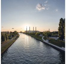 Ansicht eines Flusses mit Industriebauten im Hintergrund bei Sonnenuntergang