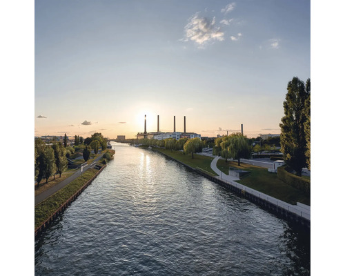 Ansicht eines Flusses mit Industriebauten im Hintergrund bei Sonnenuntergang