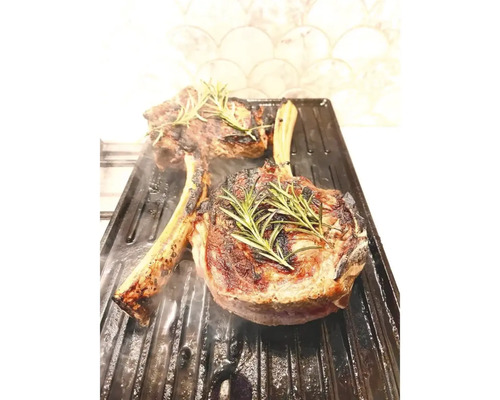 Zwei Tomahawk Steaks auf einer Grillplatte mit Rosmarin garniert