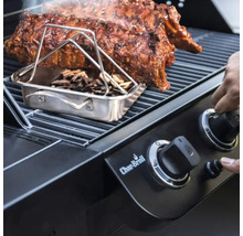 Grill mit Rippchen, Räucherbox und Holzschnipseln sowie Hand an einem Drehknopf