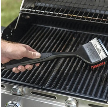 Eine Hand benutzt eine Grillbürste zur Reinigung eines Grills.