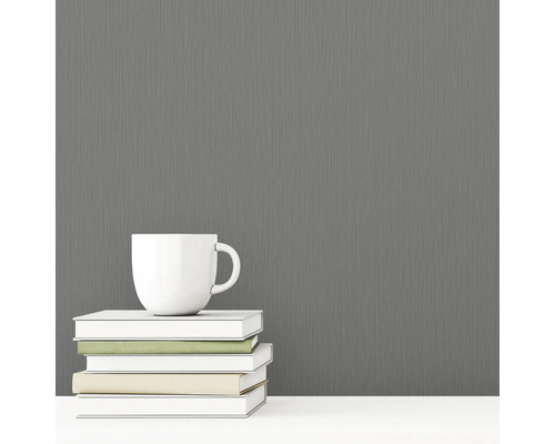 Graue Vliestapete mit Textilstruktur neben einer Tasse und Büchern