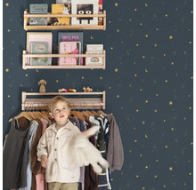 Kinderzimmer mit Holzregalen an einer mit Sternen verzierten Wand und einem Jungen vor einem Kleiderständer