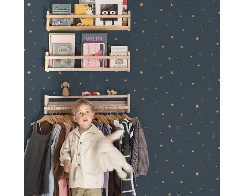 Kinderzimmer mit Holzregalen an einer mit Sternen verzierten Wand und einem Jungen vor einem Kleiderständer