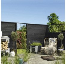 Gestalteter Gartenbereich mit Holzzaun, Pflanzgefäßen, Stuhl und Dekorationen