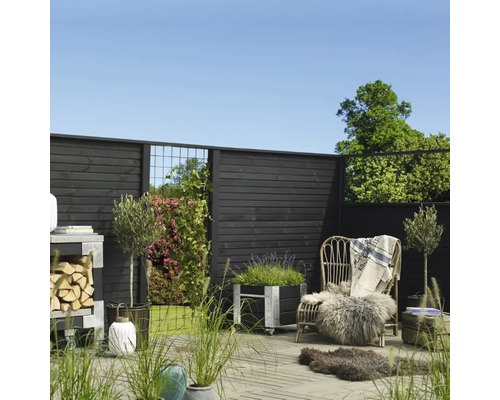 Gestalteter Gartenbereich mit Holzzaun, Pflanzgefäßen, Stuhl und Dekorationen