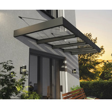 Modernes Vordach aus Glas und Metall über einer Terrassentür an einer Hauswand mit Wandleuchten und einer Holzbank.