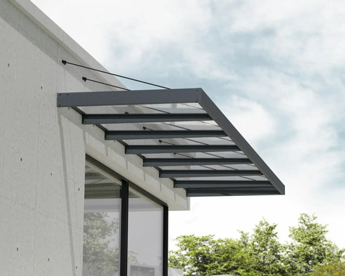 Modernes Haustürvordach aus Glas mit anthrazitfarbenem Aluminiumrahmen und Seilaufhängung an einer hellen Fassade.