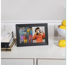 Schwarzer digitaler Fotorahmen mit Fotos von Kindern auf einem Tisch mit Büchern und Zitronen.