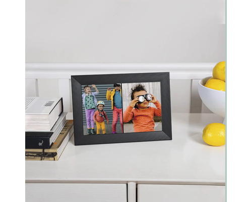 Schwarzer digitaler Fotorahmen mit Fotos von Kindern auf einem Tisch mit Büchern und Zitronen.