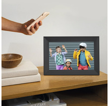 Digitaler Bilderrahmen auf einem Holzregal mit einem Foto von drei Kindern und einer Hand, die ein Smartphone hält