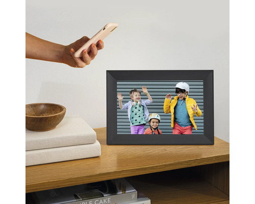 Digitaler Bilderrahmen auf einem Holzregal mit einem Foto von drei Kindern und einer Hand, die ein Smartphone hält