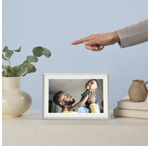 Digitaler Bilderrahmen mit Foto eines Vaters und seines Sohnes auf einem Tisch, daneben eine Vase mit Eukalyptus und eine Hand, die auf den Rahmen zeigt.