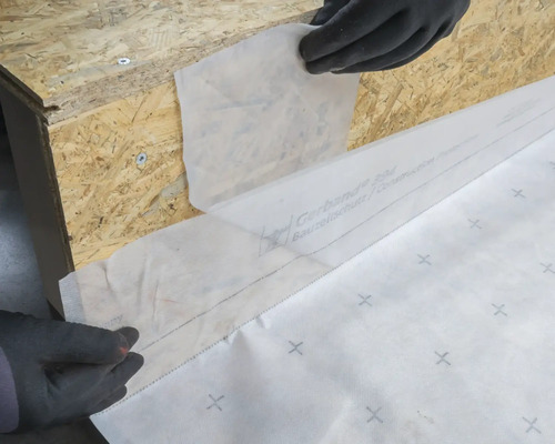 Anbringung einer Bauplane an einer Holzkonstruktion zum Schutz.