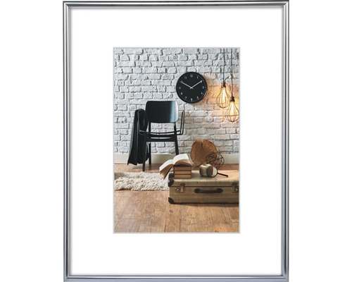 Bilderrahmen Kunststoff Sevilla silber matt Kunstglas 21x29,7 cm (DIN A4) Dekorative Szene mit Stuhl, Uhr, Lampe und Koffer vor einer Ziegelwand